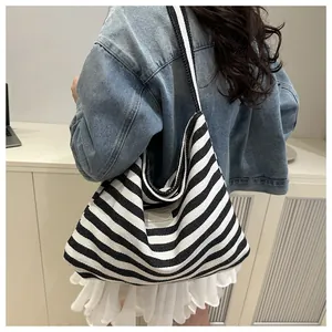 Lifestyle shot of large black and white striped canvas tote bag worn over the shoulder