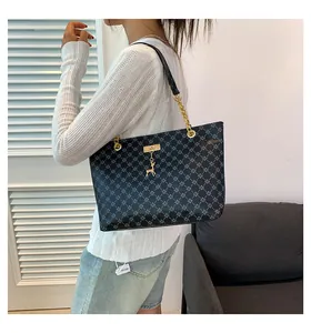 Close-up of black tote bag with blue patterns, gold chain strap and deer pendant detail