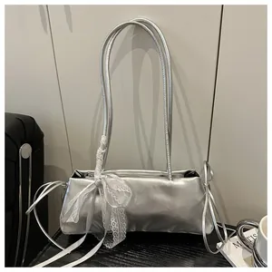 Detail of silver oil-wax leather baguette bag with white lace bow decoration