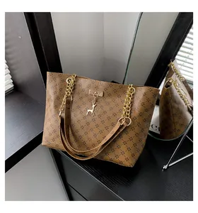 Detailed shot of brown tote bag with vintage pattern, gold chain strap and deer pendant