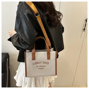 Détail du sac cabas en toile avec bordure en cuir marron et bandoulière amovible