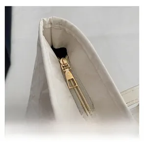 Close-up of golden zipper closure on white tote bag with cloud-like pleated texture