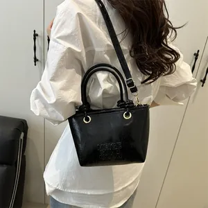 Glossy black textured bucket bag with embossed lettering and golden hardware handles