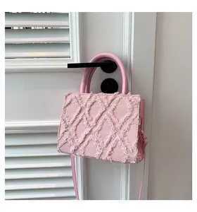 Detailed close-up of pink denim tote bag with frayed diamond texture and top handles