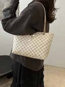 Minimalist tote bag with geometric print and metal chain strap shown on a model