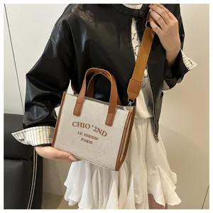Dettaglio della borsa tote in tela con finiture in pelle marrone e tracolla sul modello