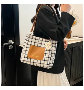 Detail of checkered tweed tote bag with brown leather pocket and cute cat pendant