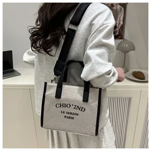 Vue détaillée arrière du sac cabas en toile beige avec finitions en cuir noir et sangle