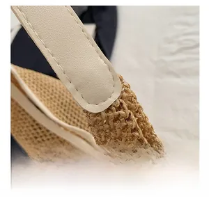 Detail shot of natural straw weaving texture and cream leather handle stitching on tote bag