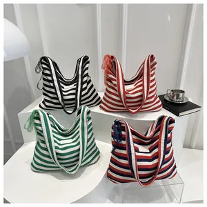 Detail of four multi-colored striped canvas tote bags with delicate lace trim accents