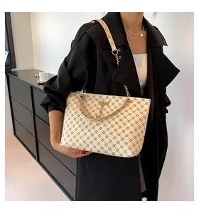Detail view of cream tote bag with star pattern, gold chain handle and wide canvas strap