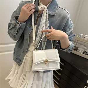 Elegante borsa a tracolla bianca con fibbia ad anello dorata indossata da una modella