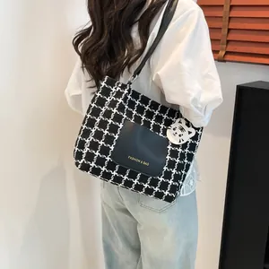 Stylish houndstooth tote bag with leather pocket shown on a model in a minimalist room