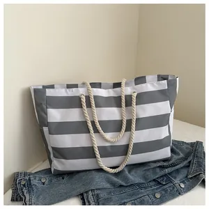 Detailaufnahme der grau-weiß gestreiften Canvas-Tasche mit gewebten Seilgriffen und Ösen