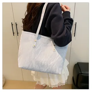 Detail of light blue tote bag featuring pleated texture fabric and gold metal rivets