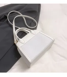 Detail view of white leather and woven fabric contrast on the minimalist pillow bag