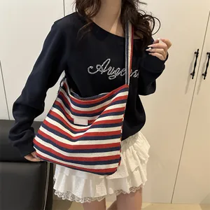 Red blue and white striped canvas tote bag with wide shoulder strap worn by model