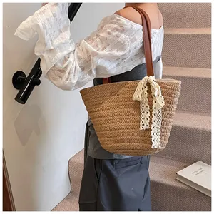Straw tote bag detail with white lace bow and dark brown leather shoulder straps