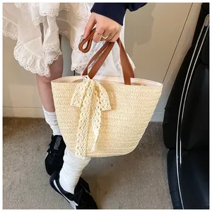 Detail of hand-woven straw tote bag with elegant lace bow and leather handles