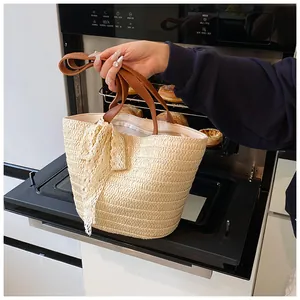 Detail of hand-woven straw tote with white lace bow and brown leather handles