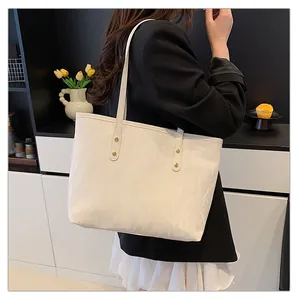 Detail of white textured leather tote bag featuring gold rivet accents and long straps