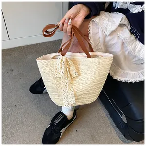 Detailed close-up of straw tote bag with brown PU handle and white lace bow detail
