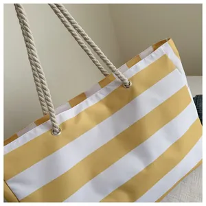 Detail der gelb-weiß gestreiften Canvas-Tasche mit dicken Seilgriffen und Metallösen
