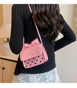 Detail view of a pink bow crossbody bag with polka dots shown on a model
