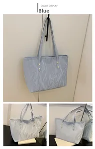 Close-up of light blue tote bag featuring water ripple texture and gold rivet details