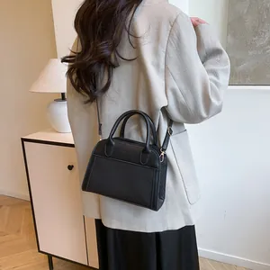 Detail showing the black leather and woven shoulder bag on model in a modern interior