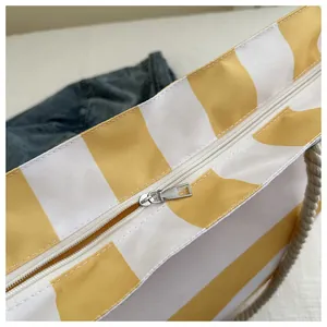 Details des Silber-Reißverschlusses und der Seilgriffe an der gelb gestreiften Canvas-Tasche