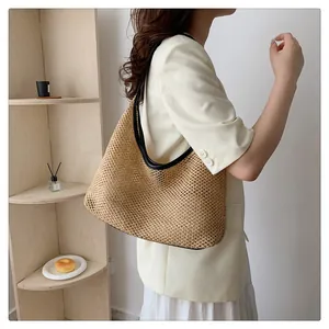 Detail of woven straw hobo bag with black trim, shown in a stylish lifestyle setting