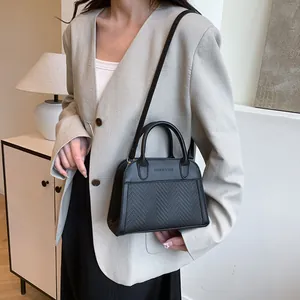 Detail of black structured tote bag featuring woven texture and embossed fashion text