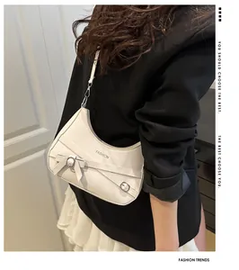 Détail du sac demi-lune blanc avec rubans décoratifs et boucle en métal argenté
