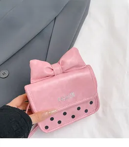 Detail of pink bow mini shoulder bag featuring embossed fashion text and dotted pattern