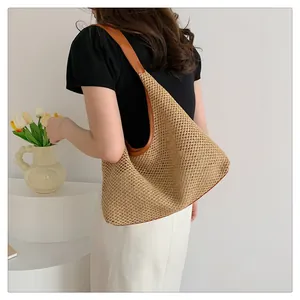 Detail of woven straw tote bag with brown leather handles and summer vacation style