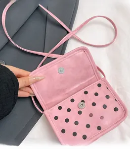 Detail view of pink polka dot mini bag featuring a secure metal magnetic snap closure