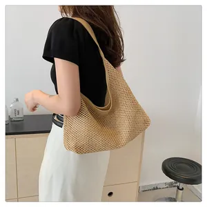 Detail of woven straw tote bag with intricate texture and shoulder strap on model