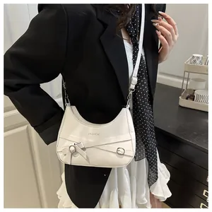 Détail du sac bandoulière demi-lune blanc avec nœud en cuir et boucle métallique