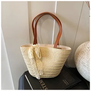 Detail of woven tote bag featuring cream lace bow and premium brown leather handles
