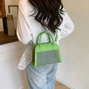 Detail of green leather and herringbone weave on a crossbody bag shown on a model