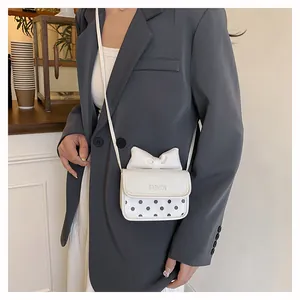 Detail of white girls' mini crossbody bag with a large bow and black polka dot pattern