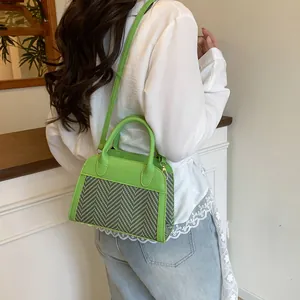 Detail of green PU leather and herringbone fabric stitching on a crossbody handbag