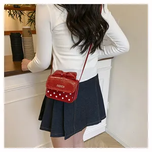 Detailed back view of a red bow crossbody bag with white polka dots on a young model