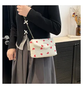 Detail of white corduroy bag with red heart patterns and decorative silk bows