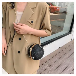 Detailed view of spherical evening bag with black glitter texture and gold metal frame