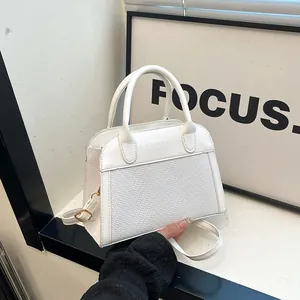 Detail of white leather handbag with woven texture and gold hardware accents