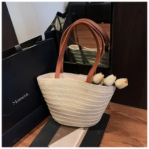 Detail of hand-woven straw tote with premium brown leather straps and floral accents