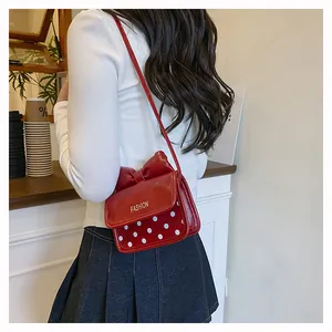 Detail view of red polka dot girl's shoulder bag with bow and gold fashion lettering