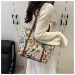 Detailed view of floral embroidery on a large canvas tote bag with brown leather straps